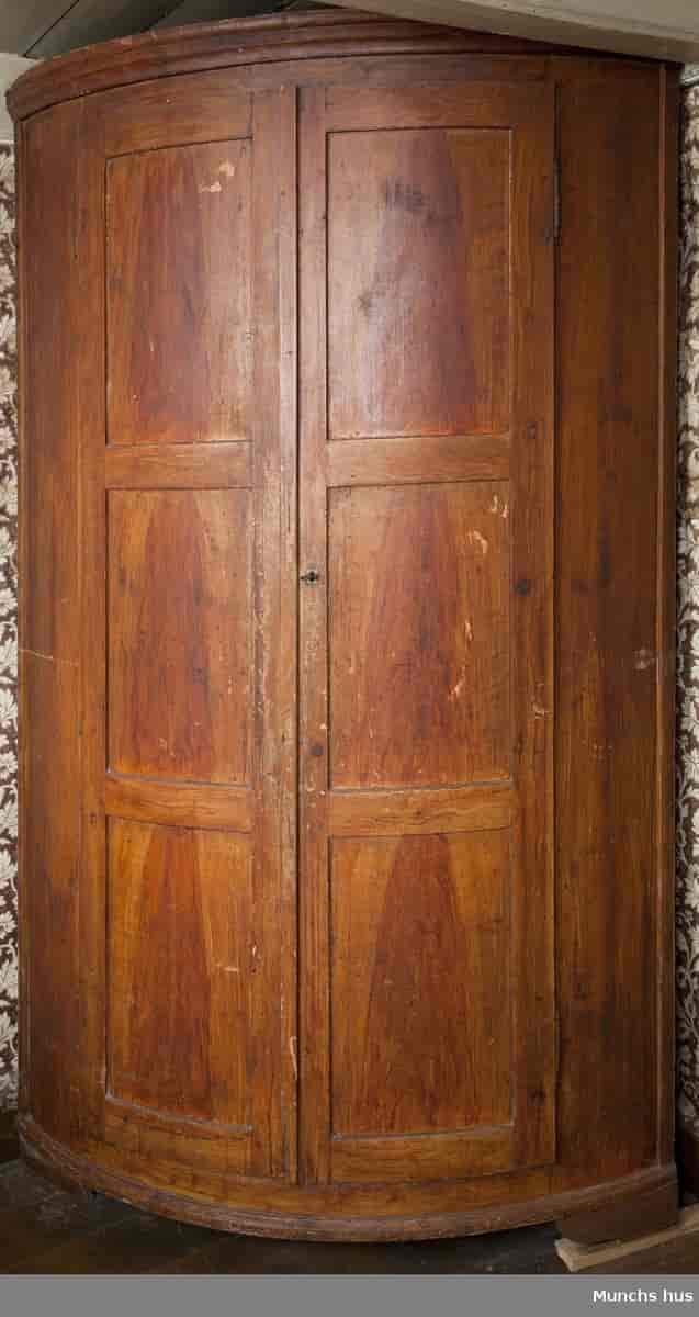 Hjørneskap med to dører og syv hyller i biedermeier-stil. Har tilhørt Edvard Munch.