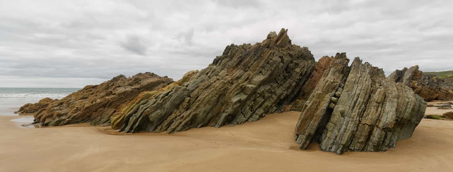 Lag fra silur stikker opp fra sandstrand, Marloes Sands, Pembrokeshire, Wales.