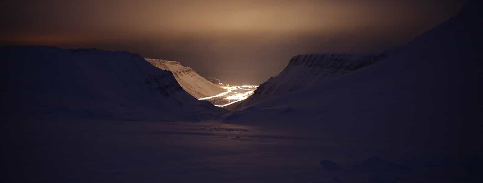 Longyearbyen i mørketid, sett imellom fjellene Sarkofagen (t.v.) og Gruvefjellet (t.h.)