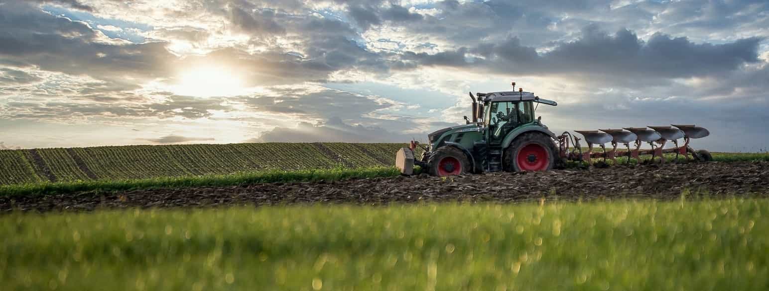 traktor kjører på jorde med plog