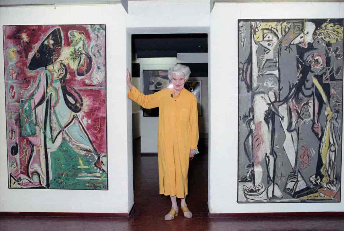 Peggy Guggenheim mellom to tidlige malerier av Jackson Pollock