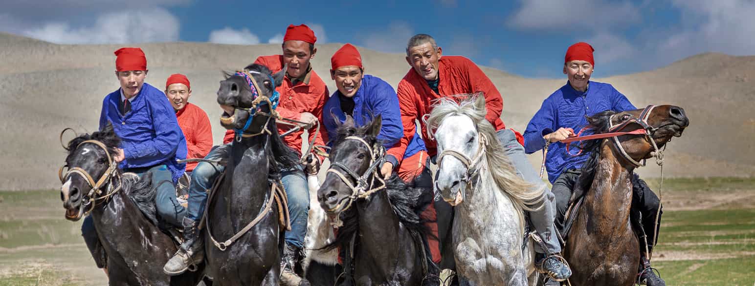 Kirgisiske menn med tradisjonelle klesplagg til hest