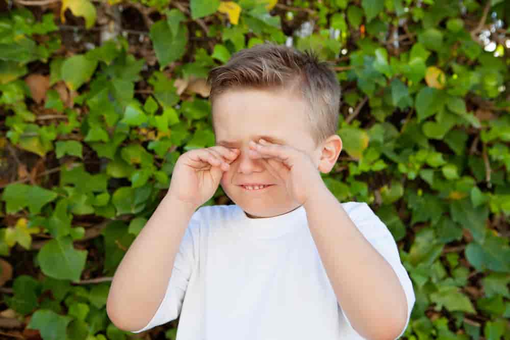 En gutt med allergi klør seg i øynene