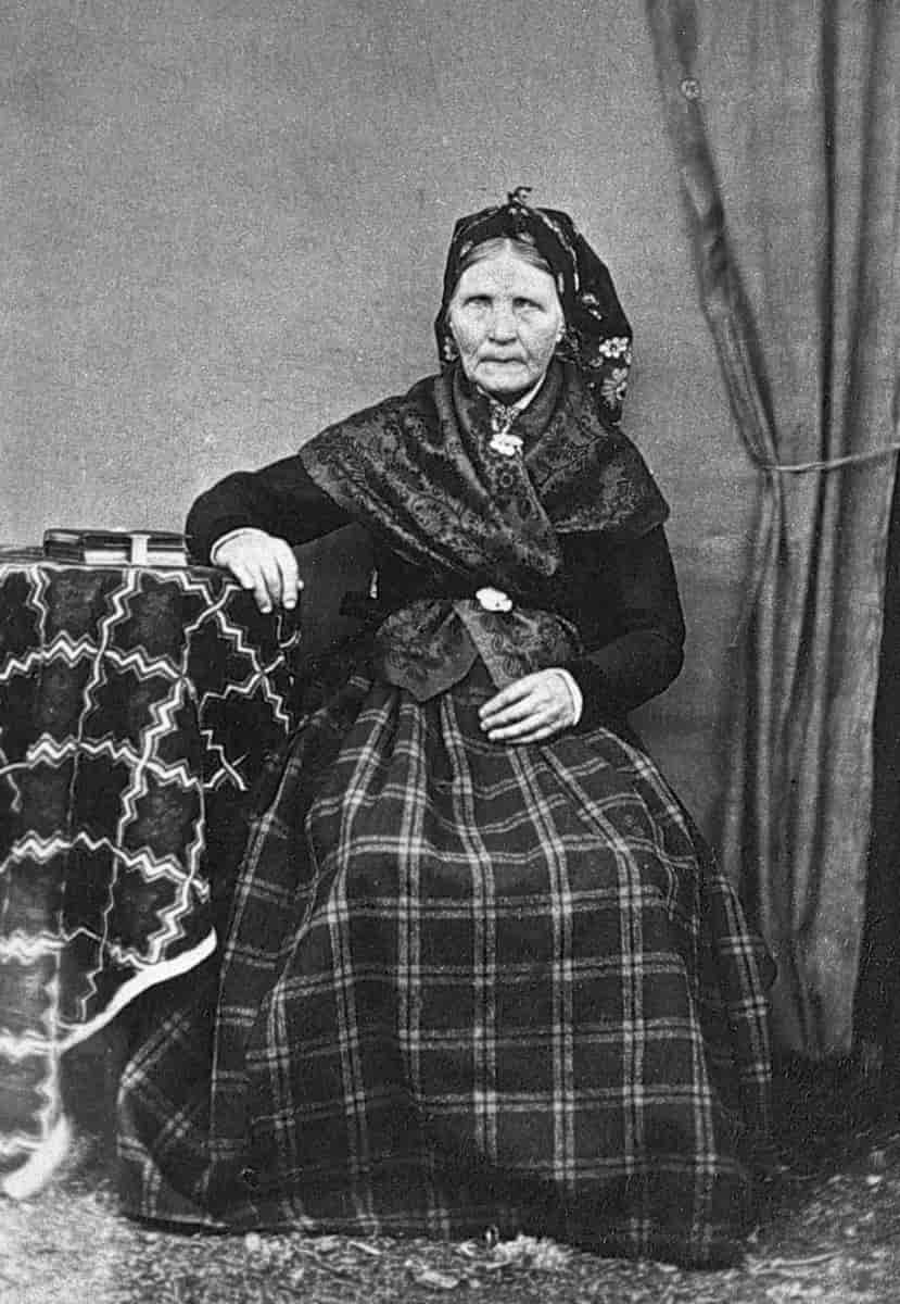 Kvinne fra Valdres, tradisjonelt kledd med rutastakk, trøye, tørkle og limpeplagg