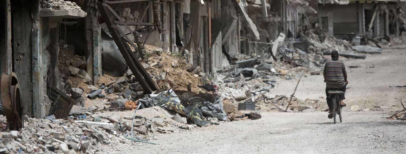 En innbygger i Homs sykler gjennom ødelagte gater i byen Homs. 