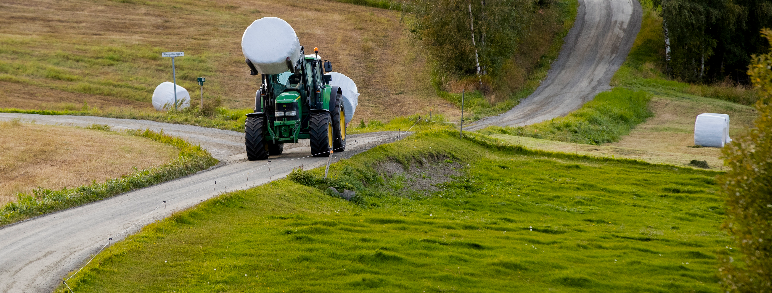 Traktor av merket John Deere frakter rundballer. Gammel-Kleppe i Vågåmo.