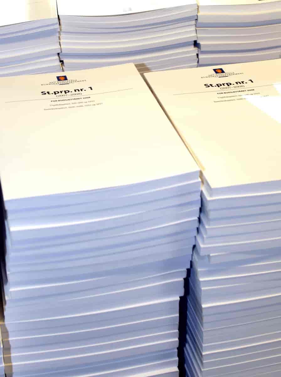 Foto av tykke dokumenter, som ligner på bøker. De ligger i stabler. På forsiden er Norges riksvåpen og teksten «St.prp. nr.1»