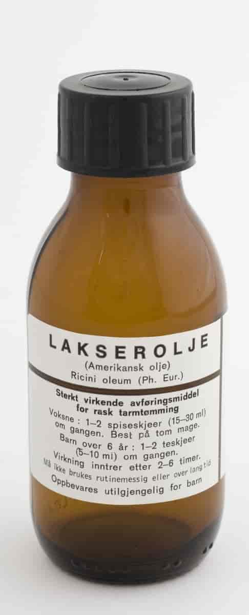 Bilde av en gammel medisinflaske med etikett. På etiketten står det at det er lakserolje og hvordan den skal brukes. 
