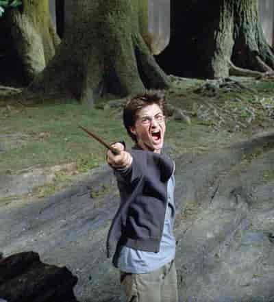 Harry Potter roper med åpen munn mens han peker en tryllestav foran seg mot noe utenfor bildet.