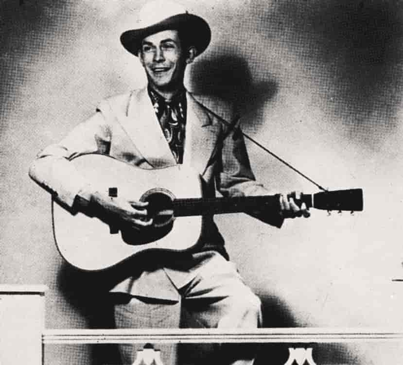 Gammelt svart/hvitt foto av musikeren med gitar og cowboyhatt.