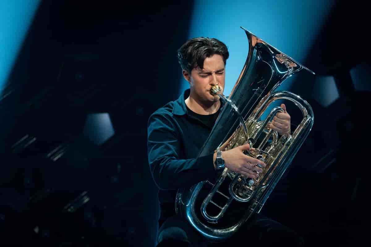 en ung mann som spiller konsentrert på en tuba.