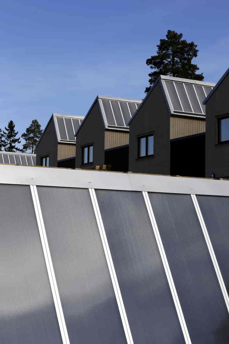 Store, avlange grå plater på taket av et hus.