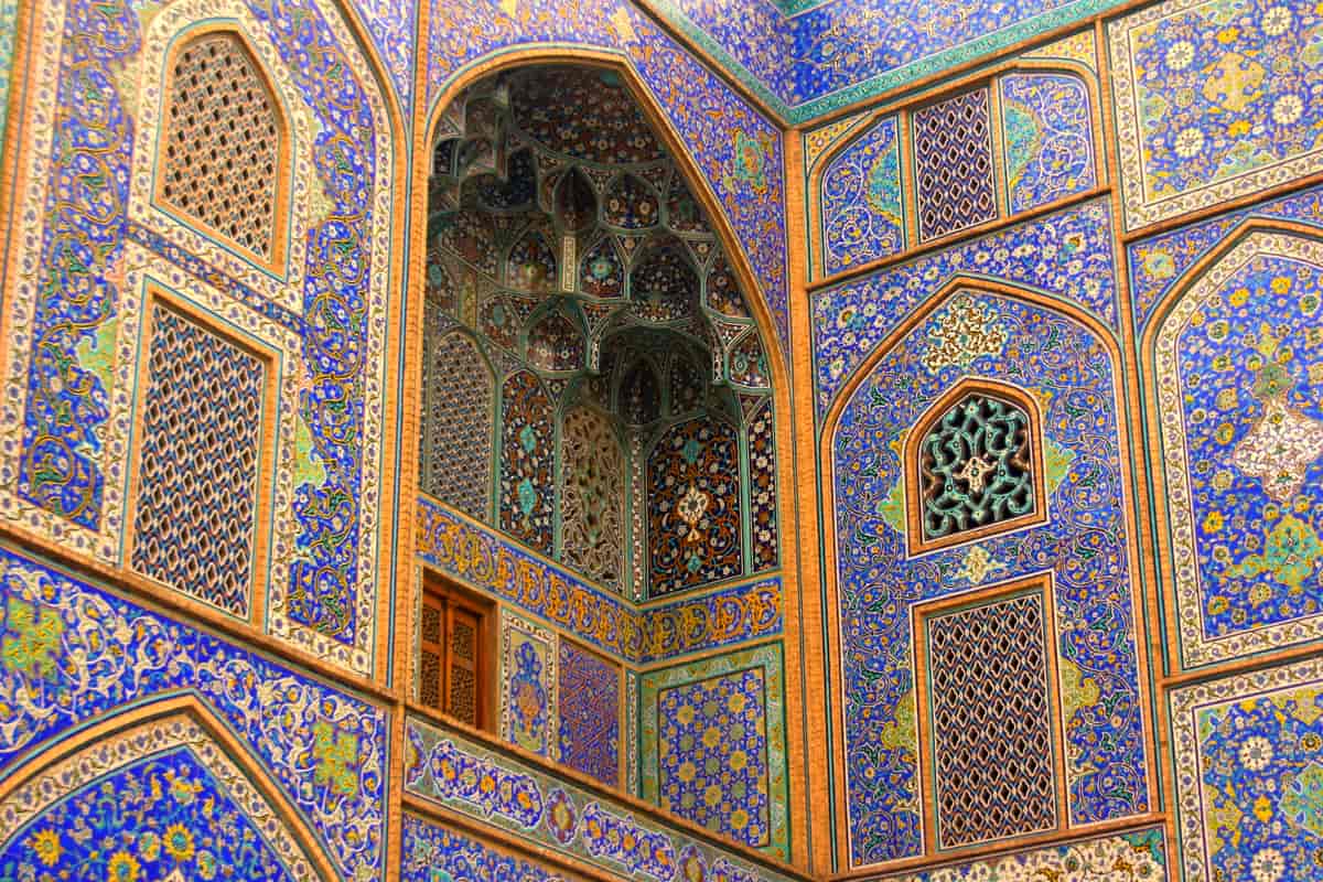 Fotografi som viser veggene inni en moské. Veggene er dekket av fargerik mosaikk, mest i blått og gull.