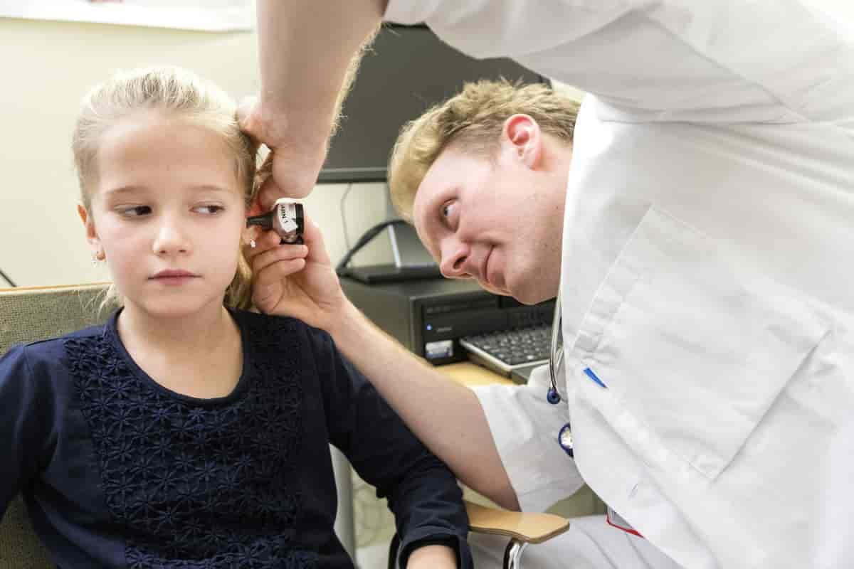 Fastlege undersøker øret til et barn med et spesielt forstørrelsesglass