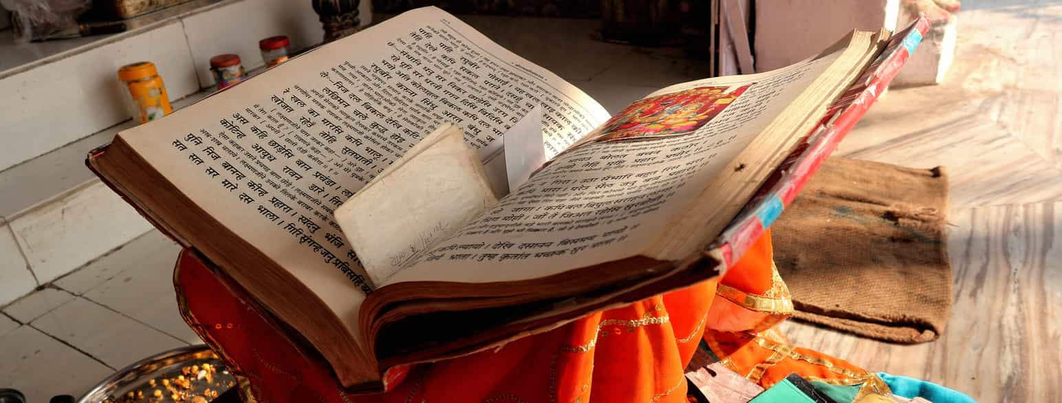 Fotografi av en oppslått bok. Boka ser gammel ut. Teksten er skrevet med indiske skrifttegn fra devanagari-alfabetet.