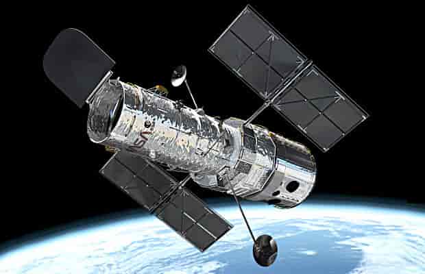 Hubble som svever ute i et mørkt verdensrom. I bakgrunnen er deler av jordkloden