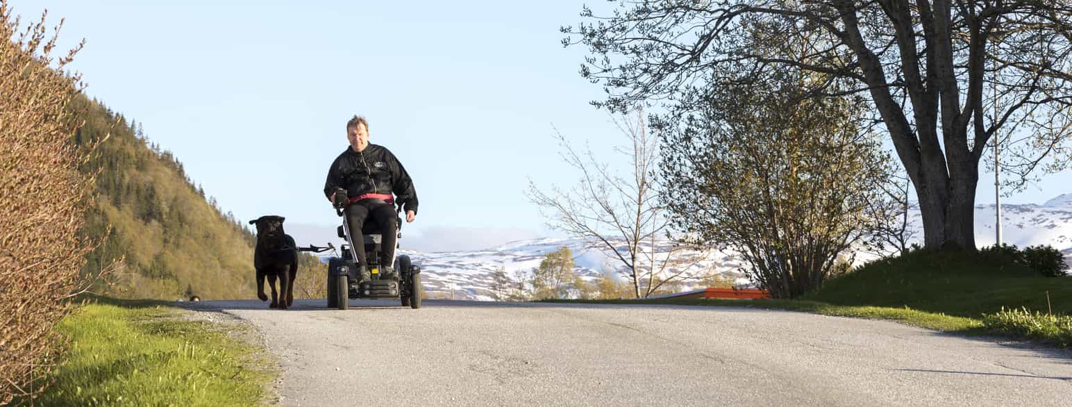 Mann i rullestol på tur med hunden