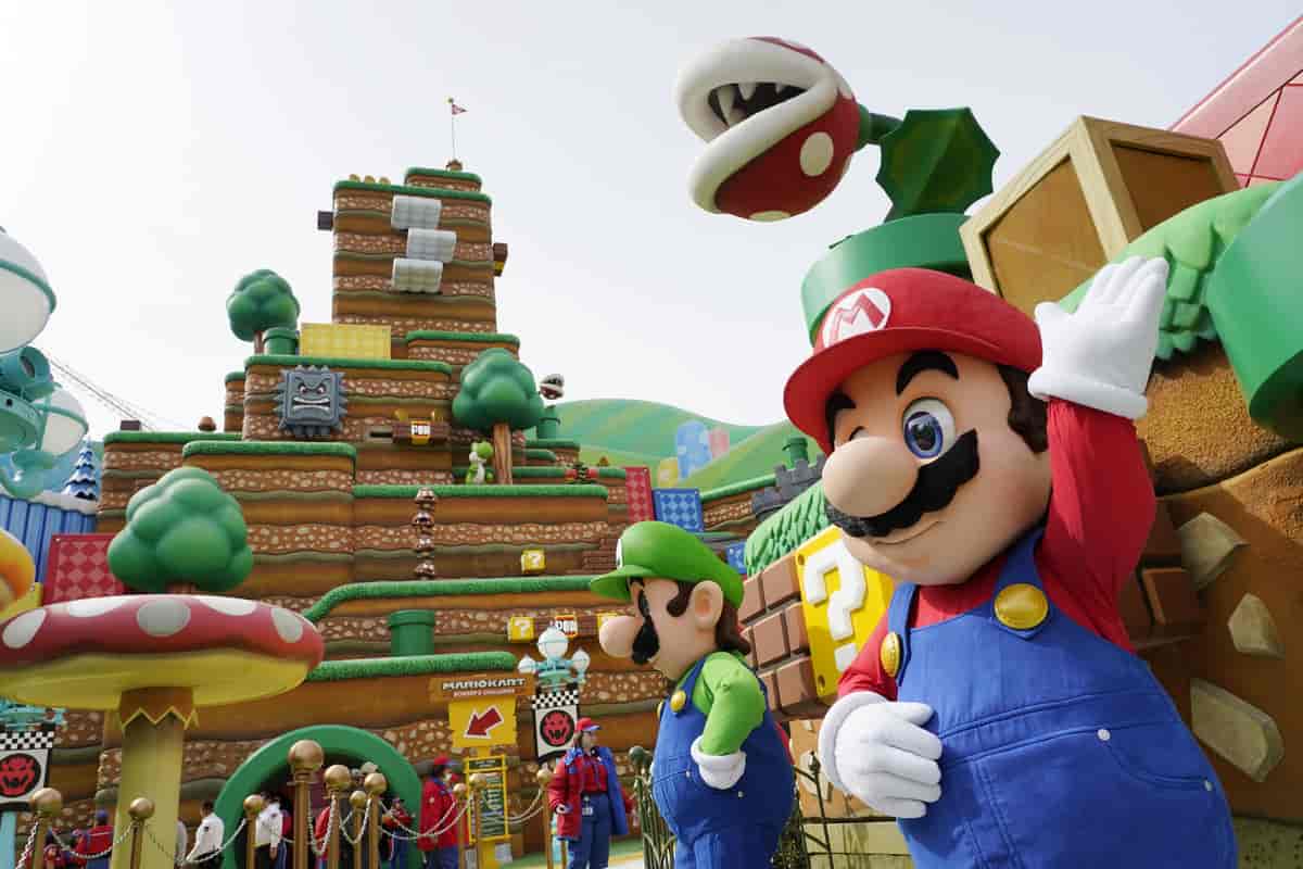 Mennesker kledd ut som spillfigurene Mario og Luigi står i en fornøyelsespark hvor det er bygget en attraksjon som ligner på deres dataspillverden.