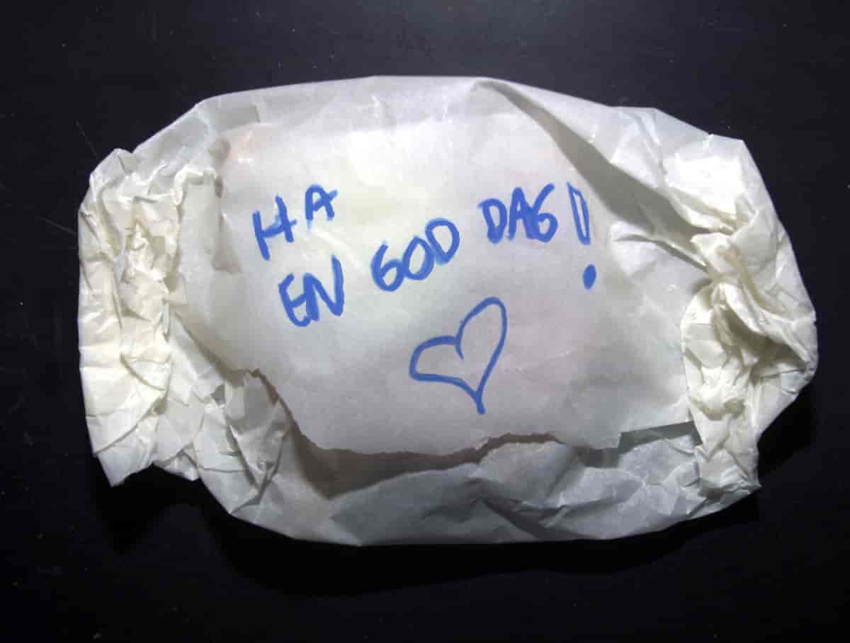 En matpakke pakket i papir med «Ha en god dag» skrevet med tusj. Foto