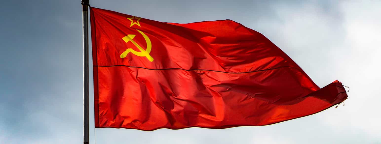 Foto av et rødt flagg med et gult symbol i øverste hjørne inn mot flaggstanga.