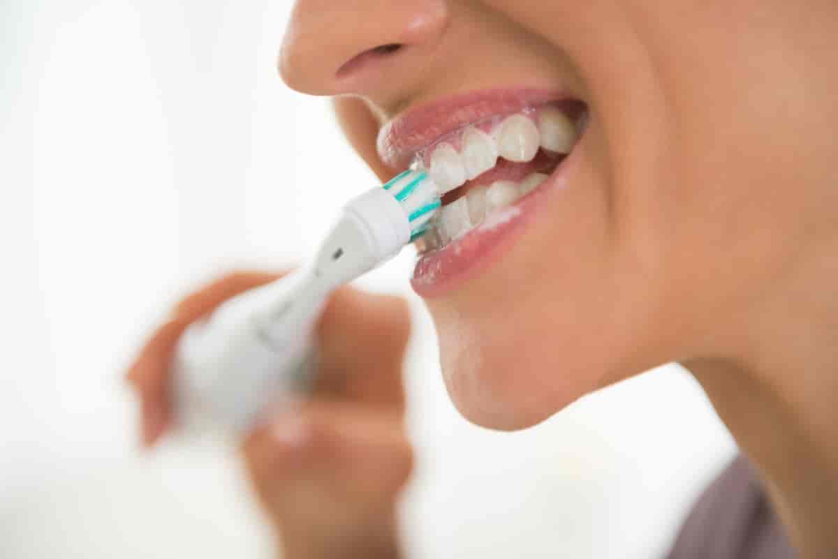 Foto av kvinne som pusser tennene med tannkrem