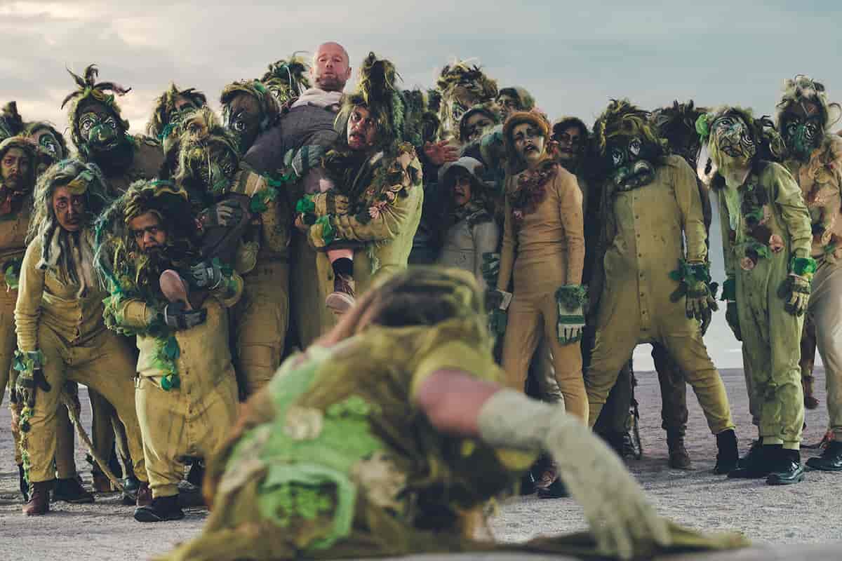 skuespillere kledd ut som troll i grønt som bærer Peer Gynt