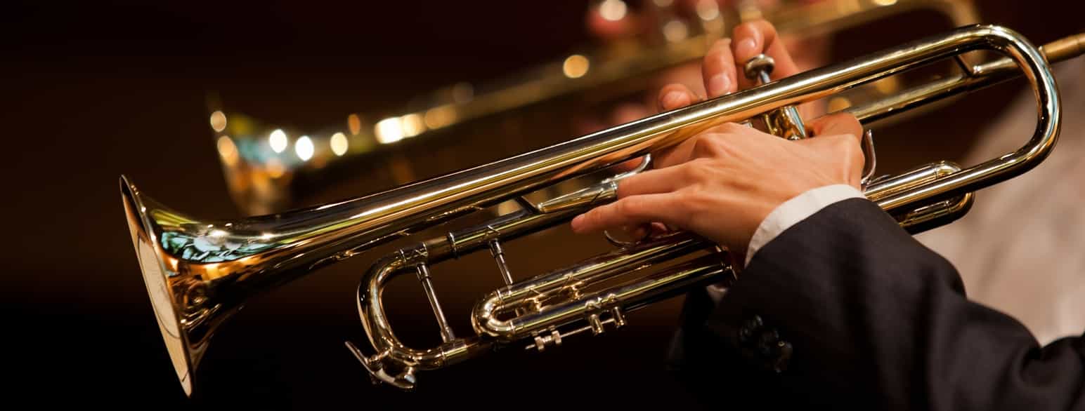 Nærbilde av hender som spiller på en trompet.