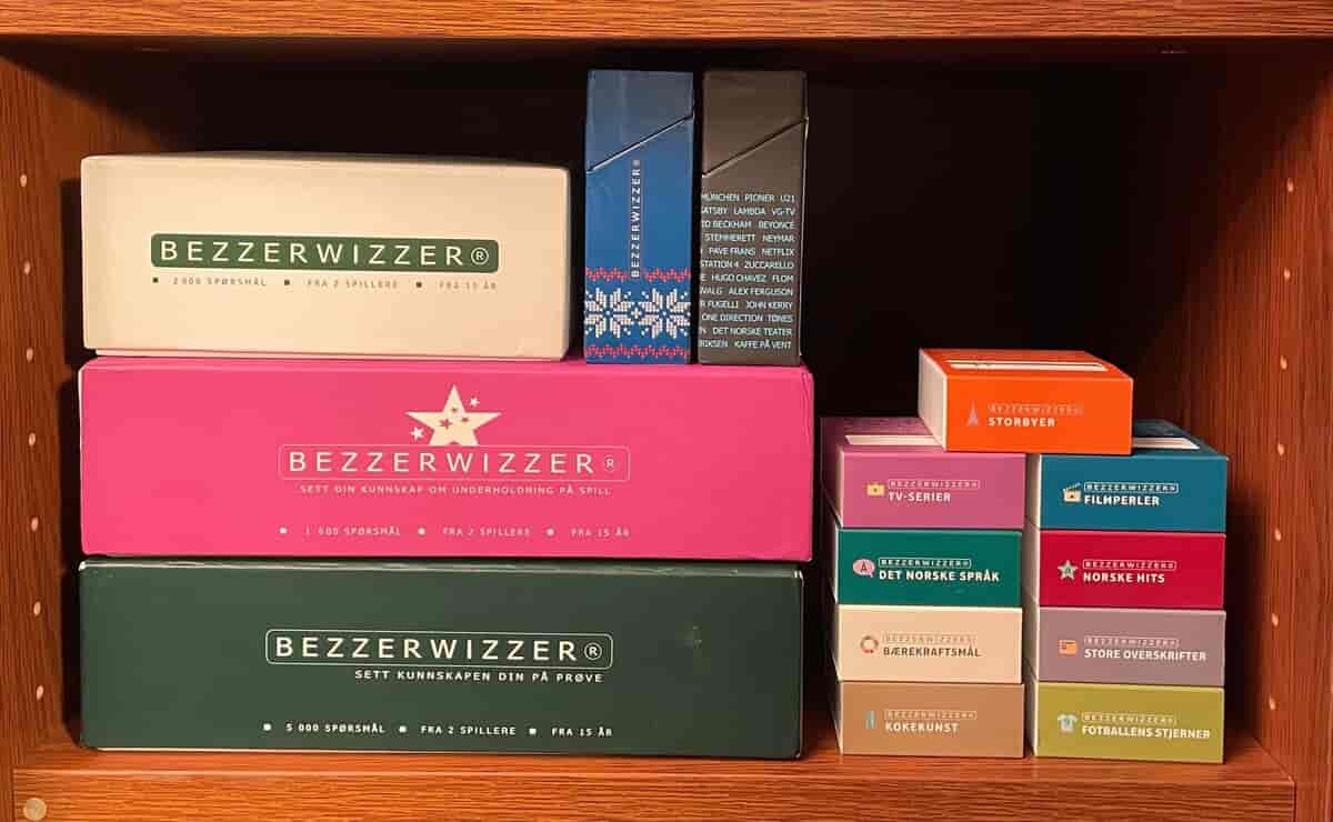 Foto av esker i forskjellig størrelse med forskjellige versjoner av spillet Bezzerwizzer som ligger i en bokhylle.