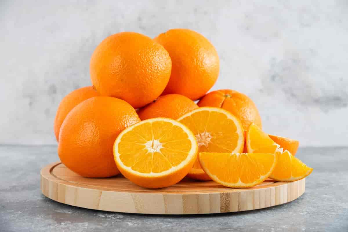 Appelsiner stablet på et brett. En appelsin er delt på tvers og i båter, så man ser fruktkjøttet. 