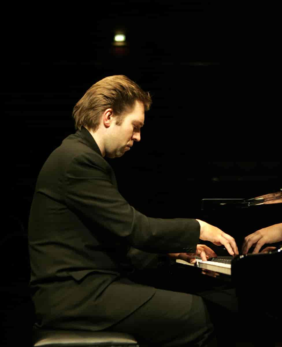 En mann som spiller med begge hender på et piano.