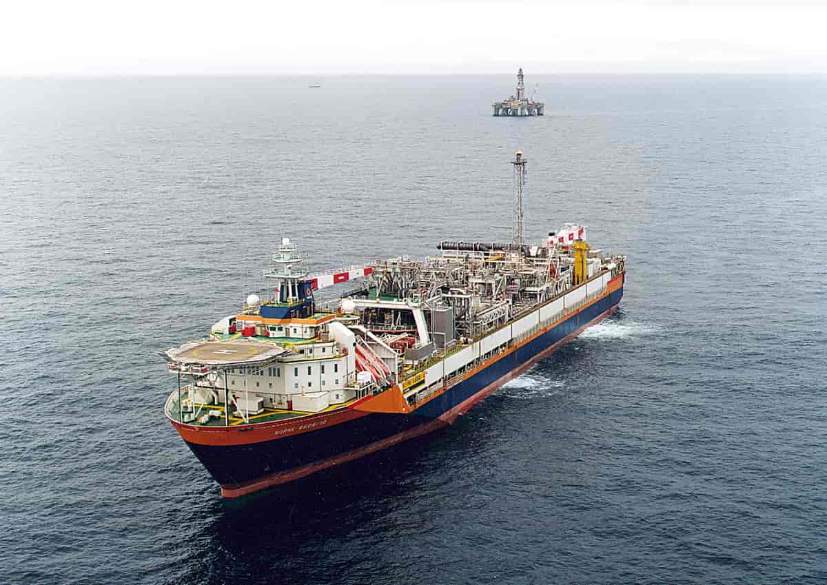 Nærbilde av Norne-skipet ute på havet. Man kan skimte en oljeplattoform i bakgrunnen.