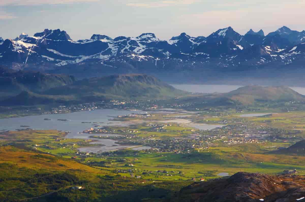 Fotografi av et slettelandskap med hus. Slettene er omkranset av fjell, og har også kyst mot en fjord.