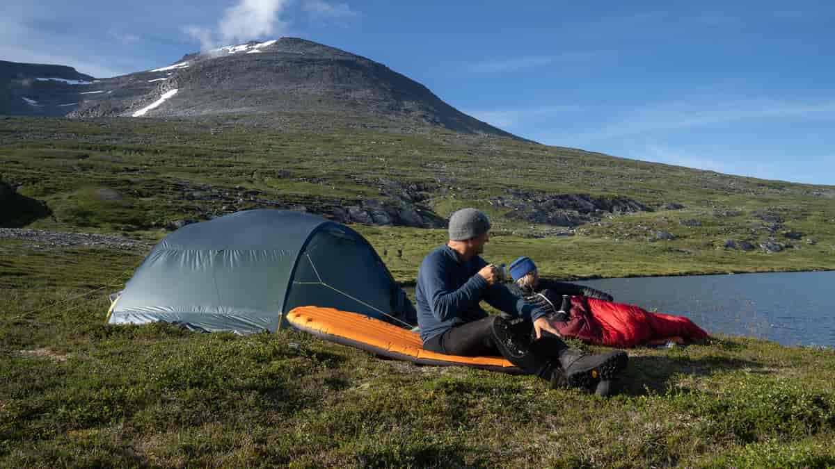 En person sitter utenfor teltet sitt på fjellet. 