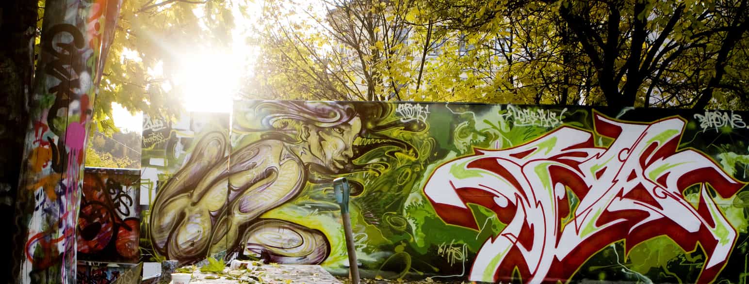 En vegg med graffiti i mange farger ute om høsten.