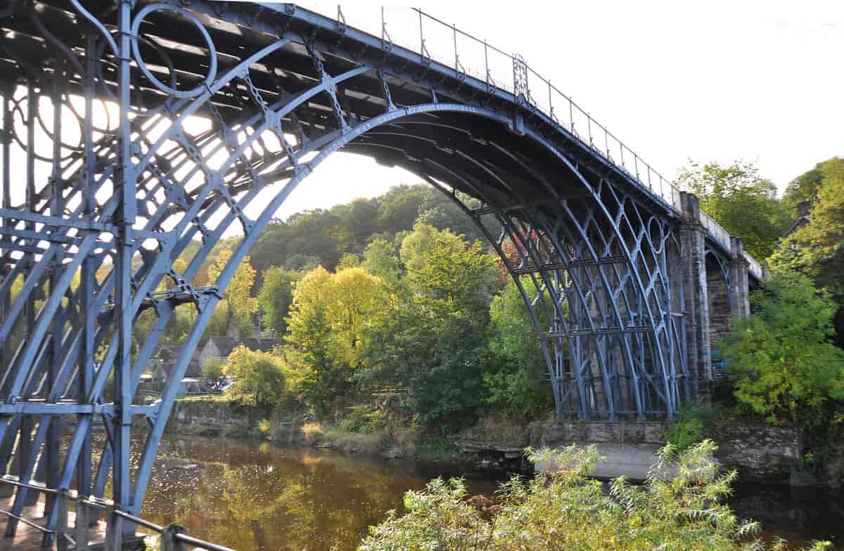 En bro over en elv. En bue av jernstenger går over elven. Oppå buen er en flatere konstruksjon. Foto