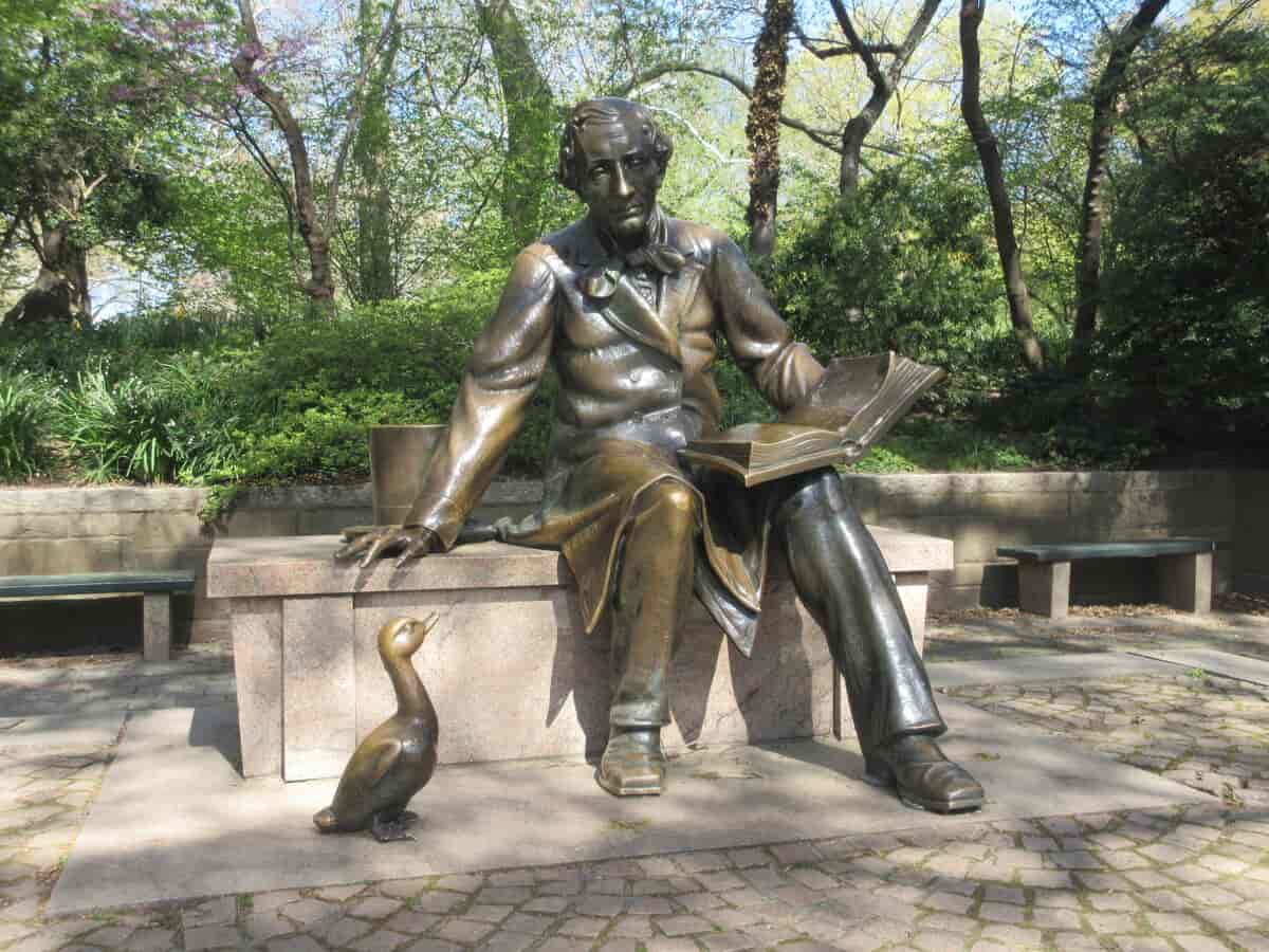 Statue i bronse av forfatteren som sitter på en steinbenk. Foran ham til venstre er en liten figur av en and.