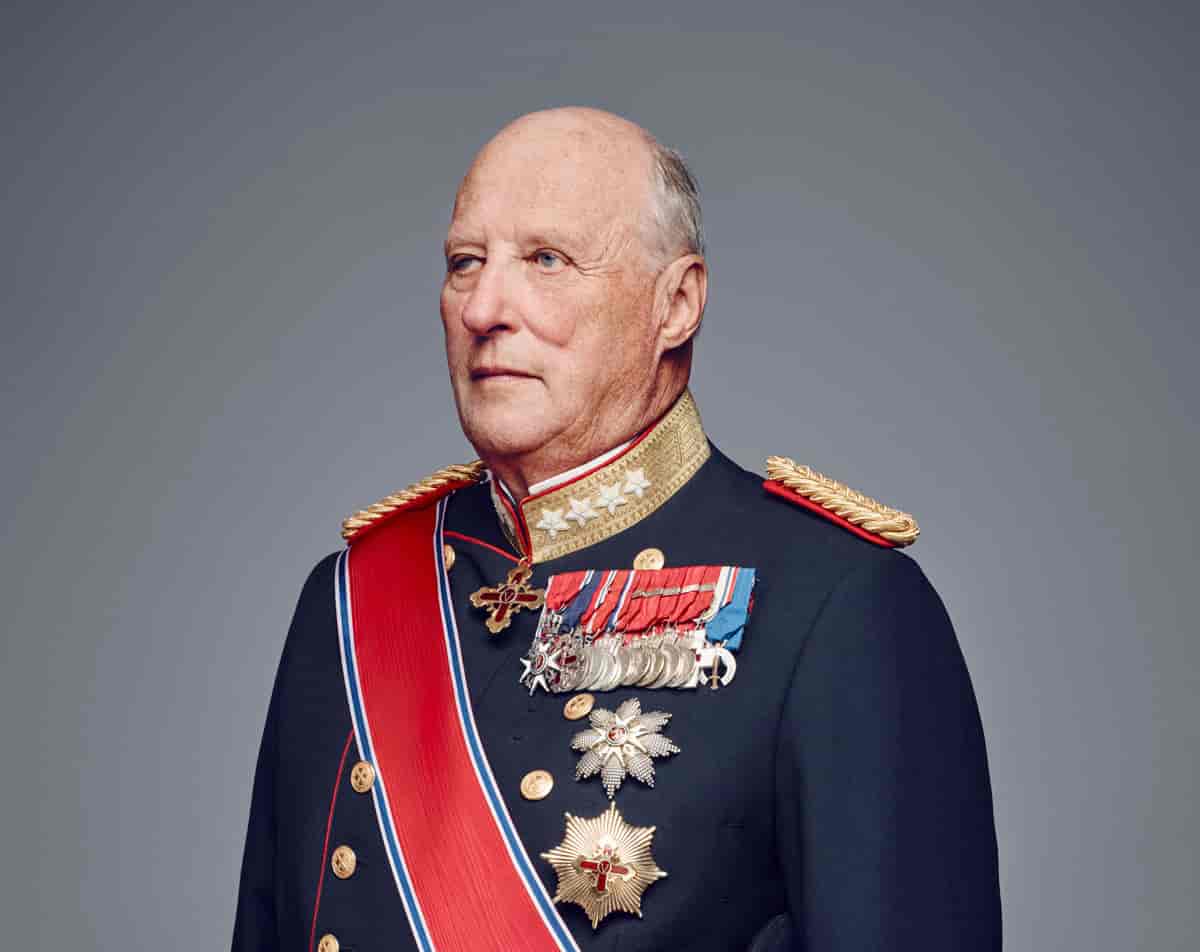 Portrett av en mann i mørk uniform med mange medaljer på brystet, et rødt ordensbånd skrått over skulderen og brystet. Foto
