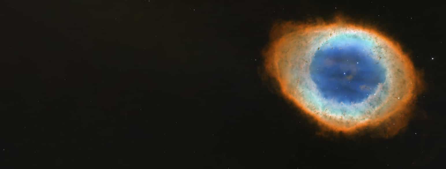 En planetarisk tåke kalt Ringtåken. Tåken blir lyst opp av en hvit dvergstjerne. Den hvite dvergen kan ses som en liten prikk i midten av tåken.