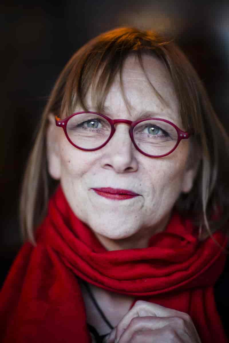 Nærbilde av ansiktet til Anne Krigsvoll med briller, røde briller, rødt skjerf of rød leppestift. 
