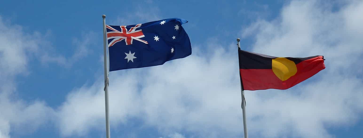 To flaggstenger med hvert sitt flagg som vaier i vinden. På den ene stangen er Australias nasjonalflagg som er blått med hvite stjerner og et union jack i det ene hjørnet. På den andre er aboriginernes flagg som er delt horisontalt i et rødt felt nederst og et svart felt øverst. Midt på er en gul sirkel. Foto