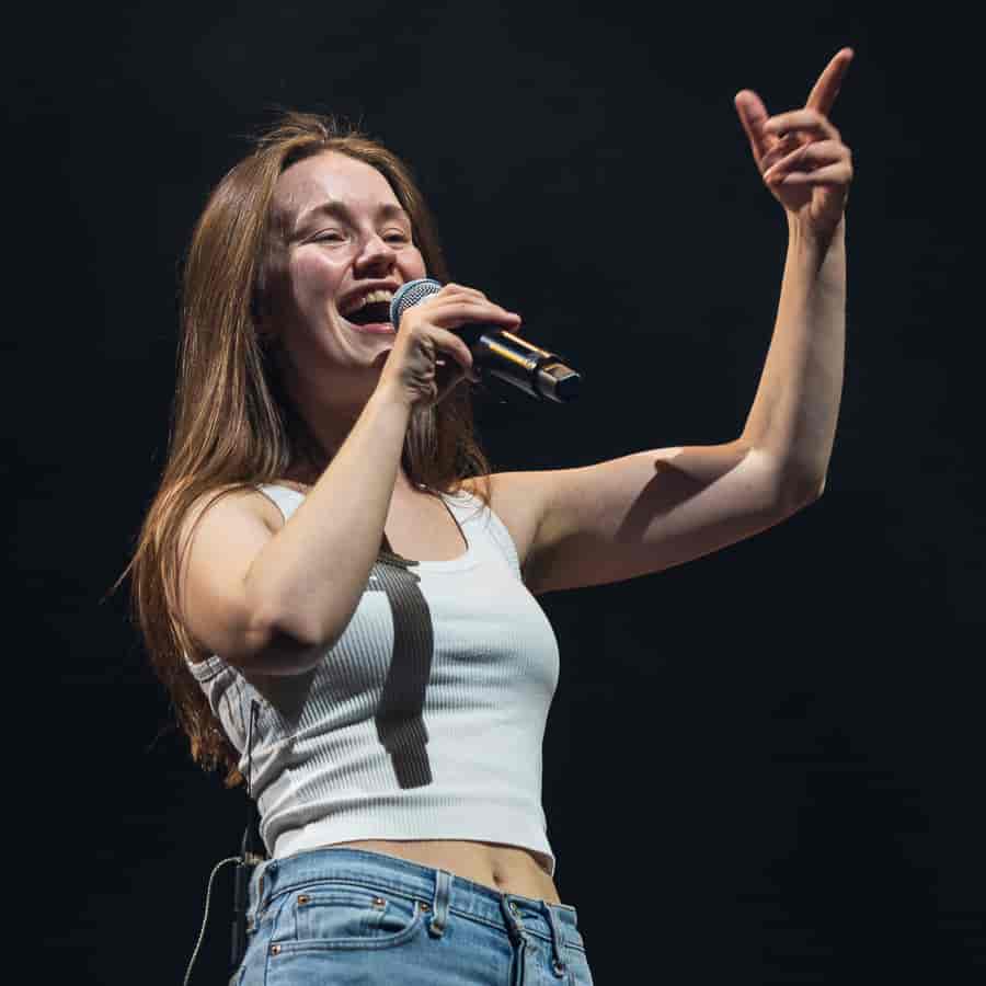 En ung kvinne står på scenen og synger inn i en mikrofon.