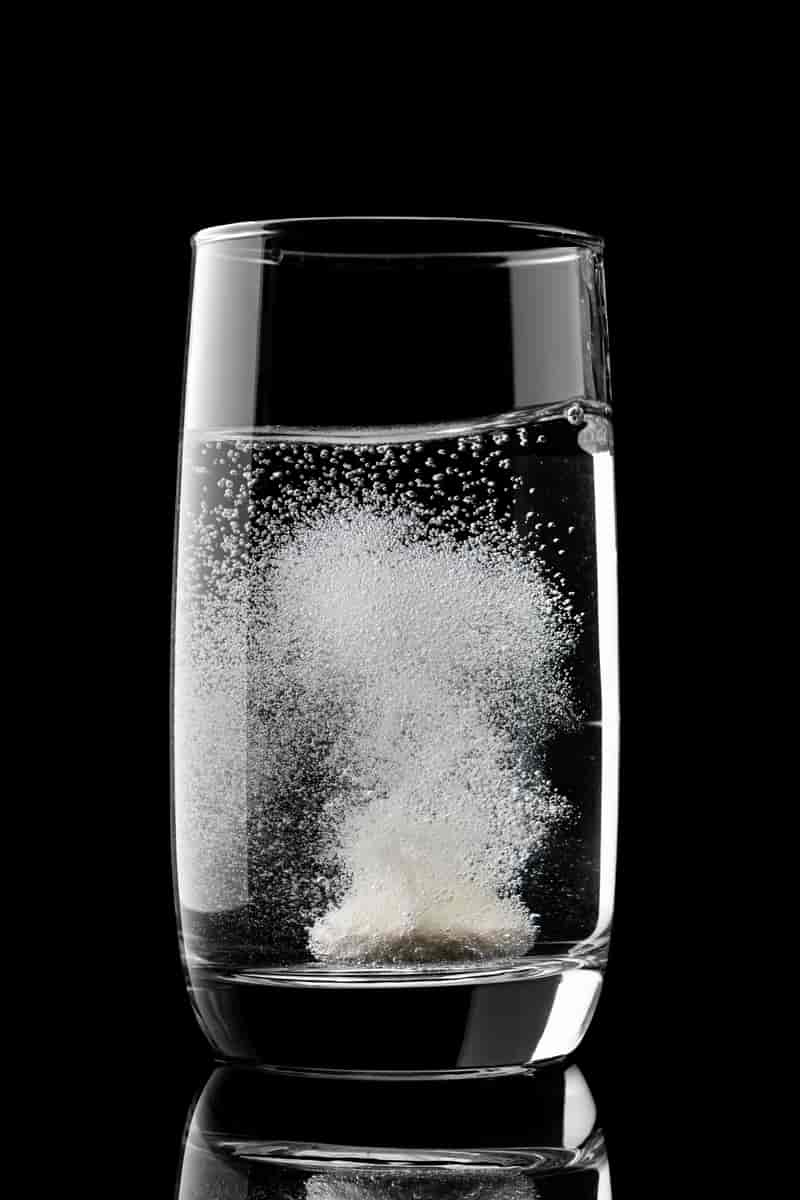 Glass vann med en hvit tablett som lager masse bobler i vannet. 