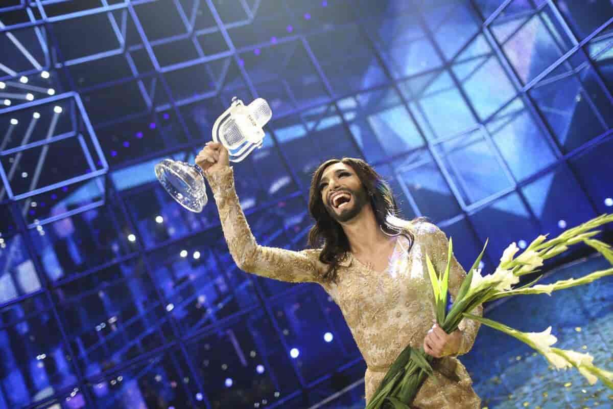 Foto av Conchita Wurst med vinnarpremien i Eurovision. Hen har gul kjole, sminke og skjegg.