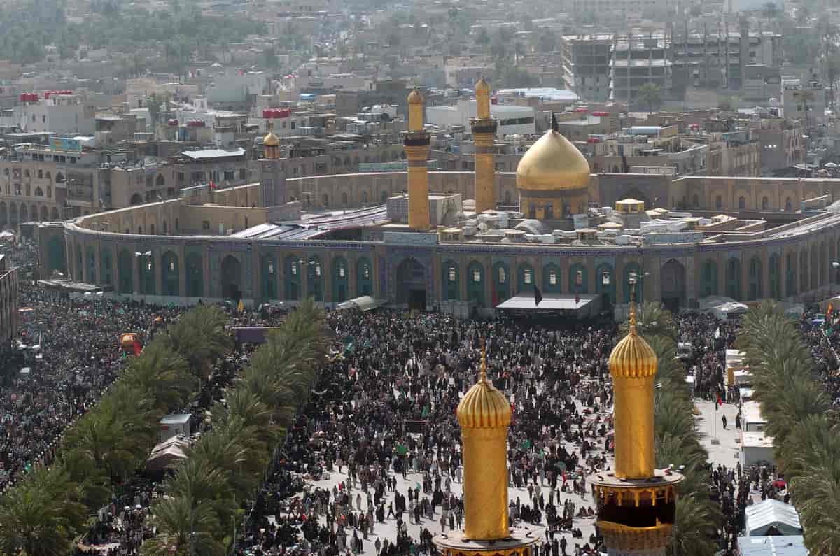Flyfoto av en veldig stor moské med en høy mur rundt. Man ser en stor folkemengde utenfor muren. Kuppelen og tårnene på moskeen er gullfarget.