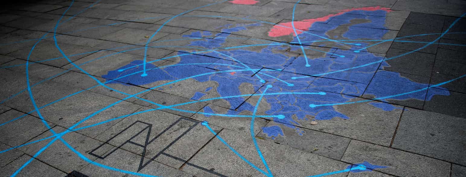En utendørs plass med steinheller. På hellene er det malt et Europa-kart med Norge og Island i rødt og resten av landene i blått. Over kartet er det malt linjer i lyseblått. Foto