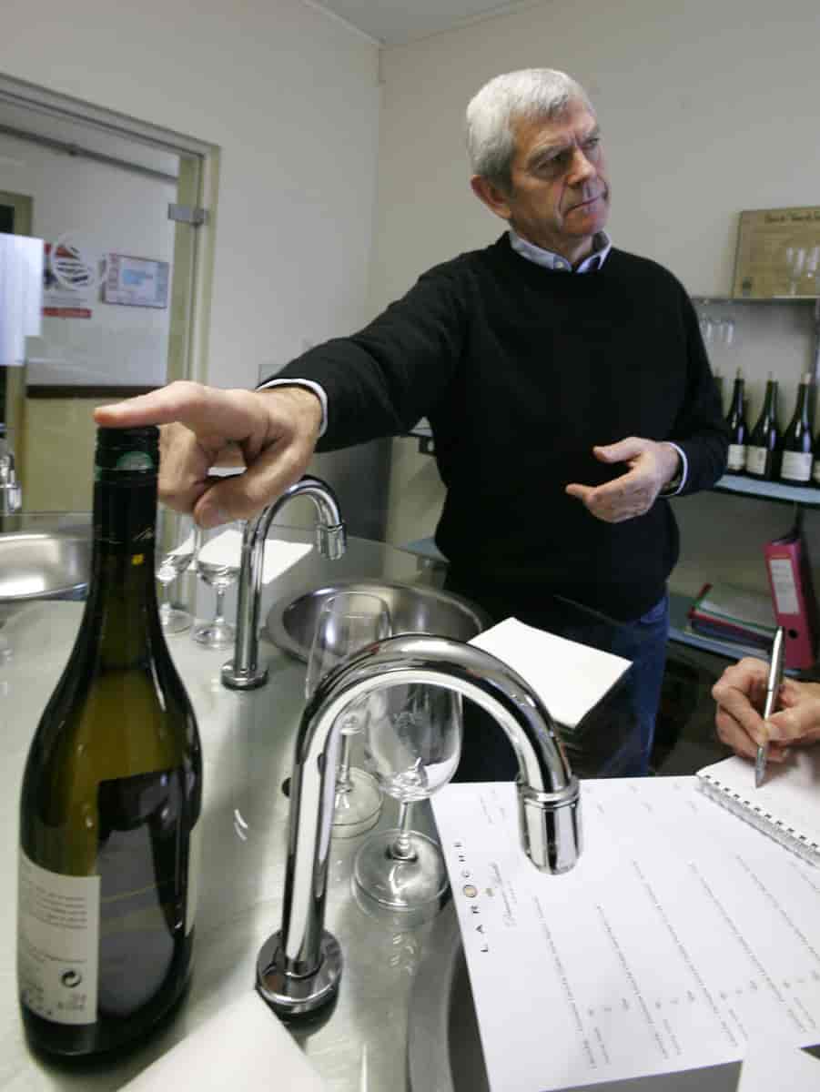 Vinprodusenten Michel Laroche står med en vinflaske med skrukork. Han var den første som satte skrukork på Grand Cru-vinflasker. 