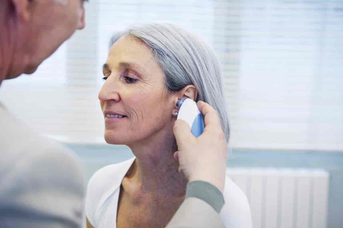 Eldre kvinne får målt temperaturen i øret. 