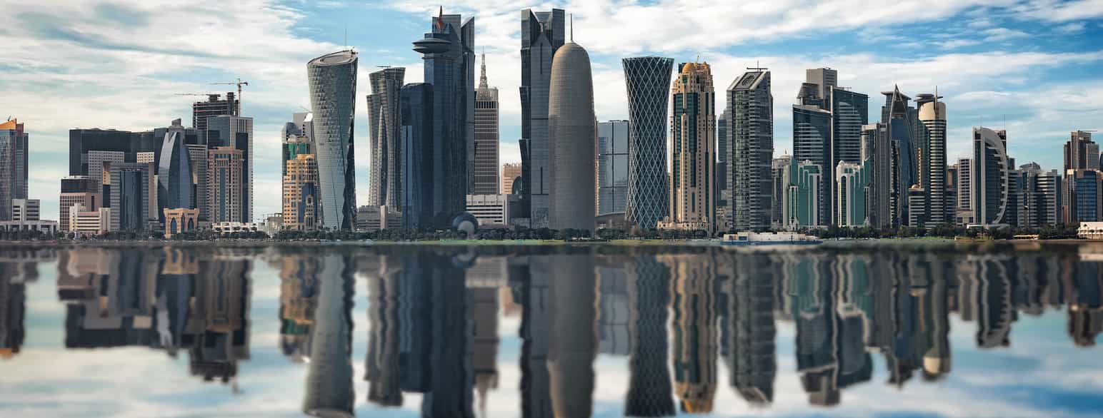 Skyline i Doha. Moderne skyskrapere som speiler seg i vannet. Foto