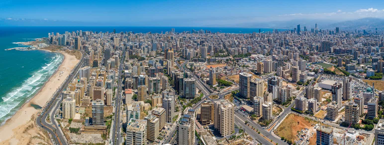 Oversiktsbilde over Beirut. Til venstre i er en strand og Middelhavet. Byen som strekker seg ut over et stort, flatt område. I horisonten er det fjell. Foto