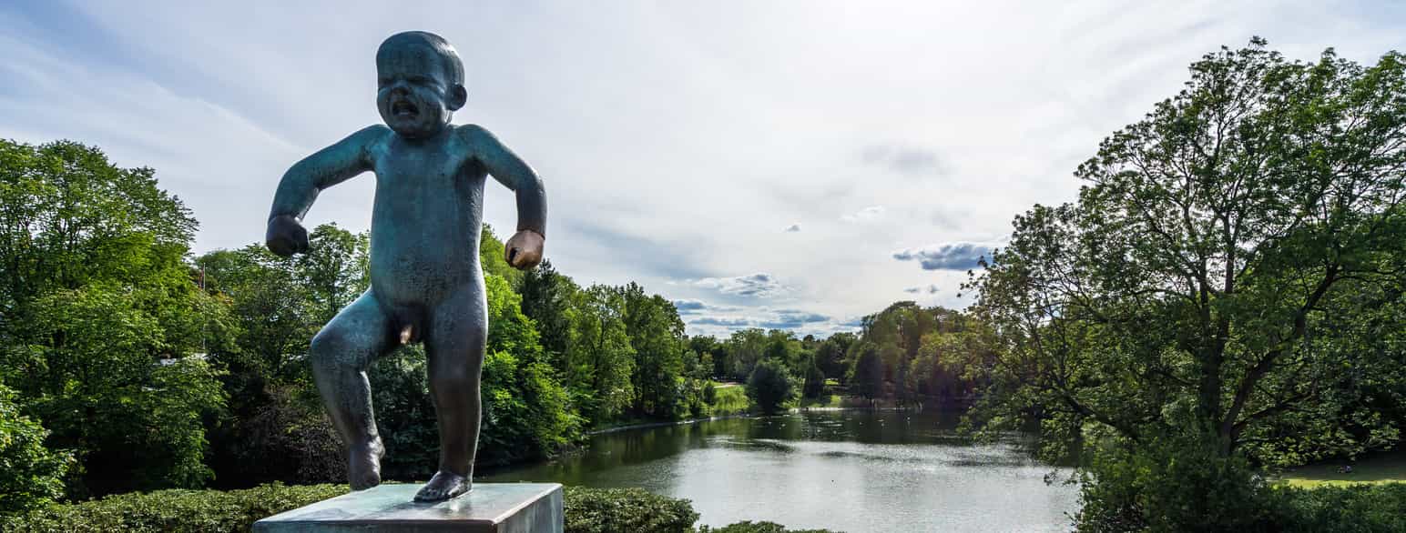 Frognerparken i Oslo. En bronsestatue av en liten gutt som står på et ben og har et uttrykk i ansiktet som om han gråter. Foto